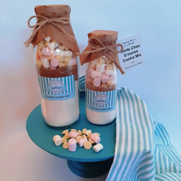 Two bottles of cookie mix with marshmallows on a blue stand against a light blue background.