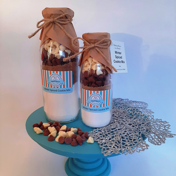 Two glass bottles filled with cookie mix on a blue stand with decorative elements.